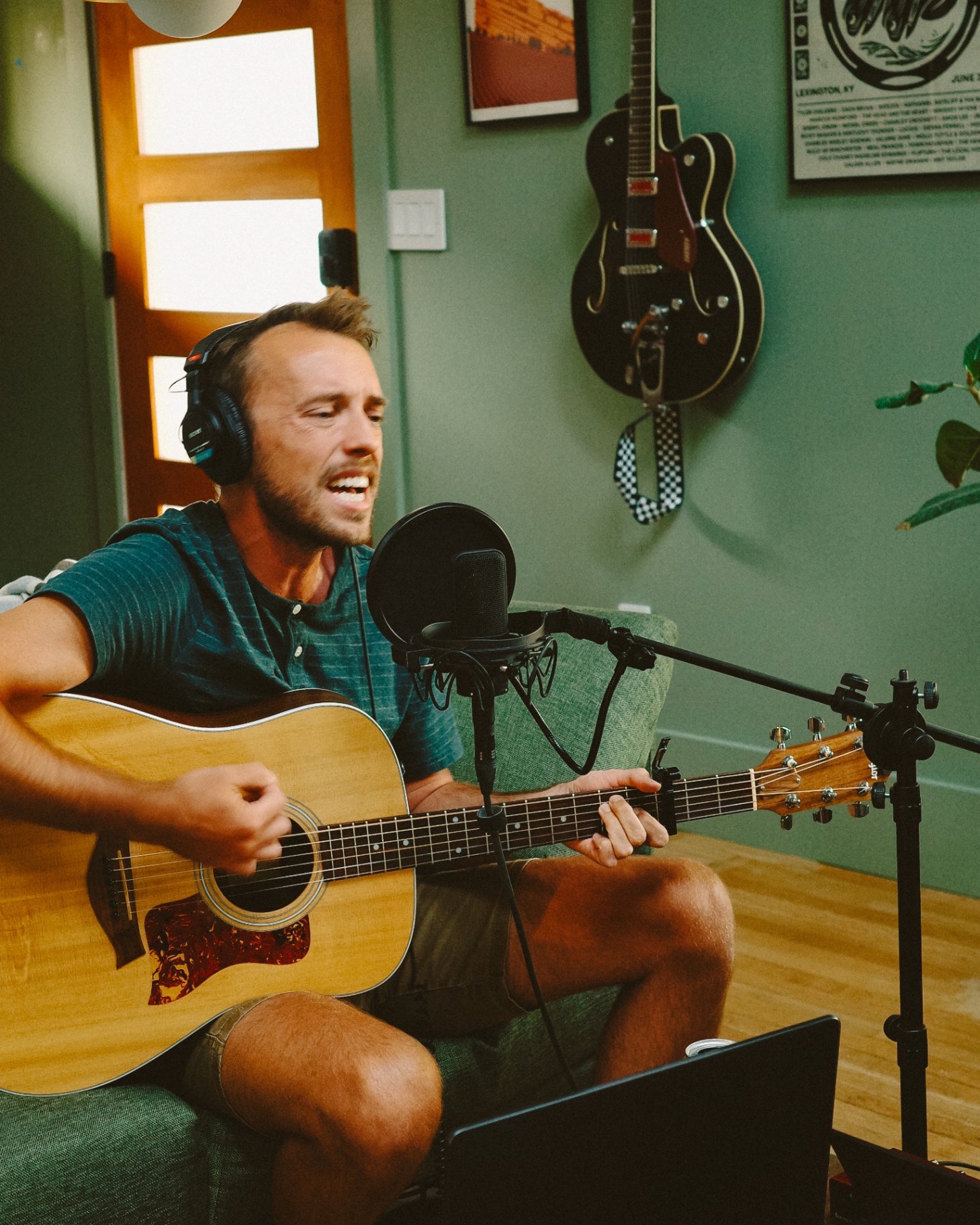 Vocalist sitting on couch singing into microphone
